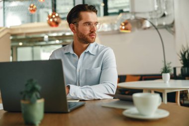 Modern ofiste dizüstü bilgisayar üzerinde çalışırken kahve içen meşgul bir erkek yönetici. Yüksek kalite fotoğraf