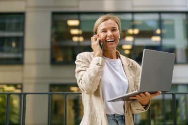 Businesswoman talking with client and work on laptop outside of office. Distance work concept 