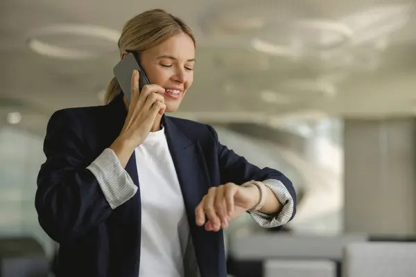 stock image Businesswoman looking at her wristwatch to checking the time while having a phone call with client