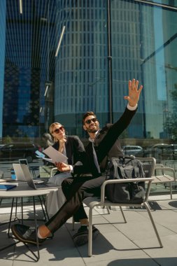 Kafe terasında ofis dışında belgelerle çalışan iki iş ortağı.