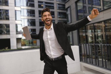 Ofis terasında dizüstü bilgisayarı olan şık bir erkek yönetici. Yüksek kalite fotoğraf