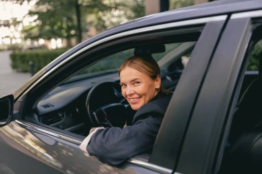 Takım elbiseli kadın sürücü direksiyonda ve kameraya bakıyor. Yüksek kalite fotoğraf