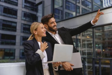 İş arkadaşları dışarıda gökdelenlerin arka planında otururken proje üzerinde çalışıyorlar