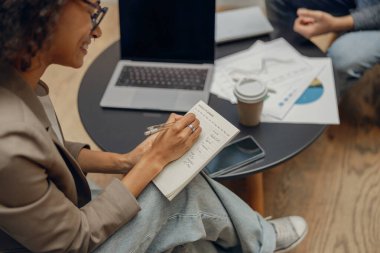 Kadın yönetici, çalışma alanındaki meslektaşıyla yaptığı toplantıda notlar alıyor.