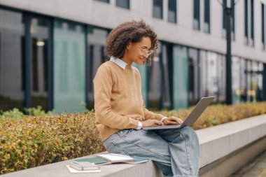 Gözlüklü zeki genç kız arka planda bilgisayar kullanıyor.