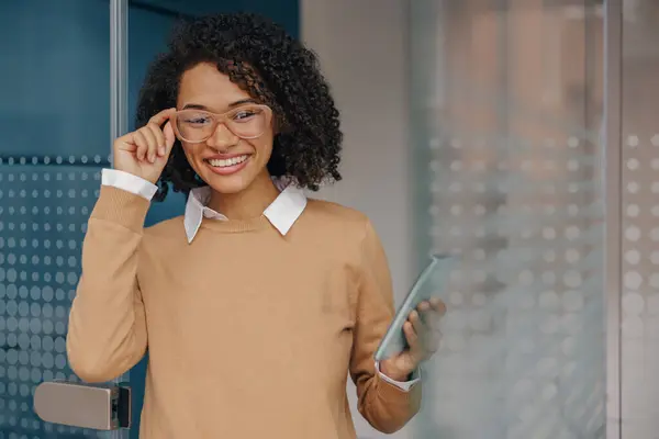 Smiling woman executive manager is using mobile phone standing in office during break time