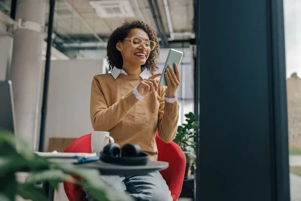 Smiling woman executive manager is using mobile phone sitting in office during break time