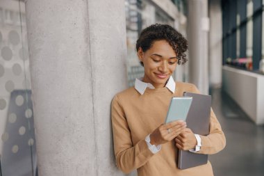 Gülümseyen kadın yönetici, tatilde ofiste cep telefonu kullanıyor.