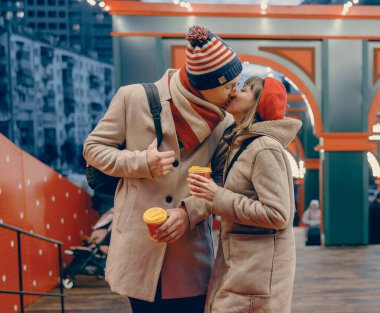 Sihirli bir Noel pazarı, çiftler için mükemmel bir arka plan görevi görüyor. Şefkatli bir öpücük, tatil ışıkları romantik anlarını ısıtıyor.