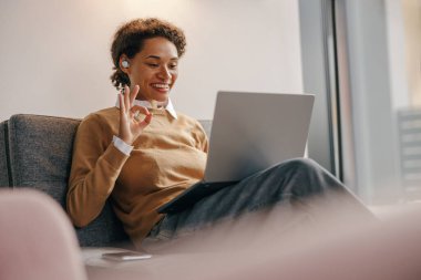 Pozitif kadın serbest çalışan gün boyunca rahat bir iş yerinde otururken online toplantı yapıyor.