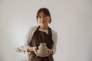 Kendine güvenen girişimci kadın çömlekçi stüdyoda kameraya bakıyor. 