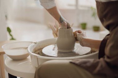 Çömlek atölyesinde kil kasesini şekillendiren zanaatkârların ellerine yakın çekim. Çömlek sanatı ve yaratıcılığı