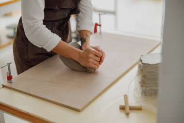 Çömlek atölyesindeki ahşap masada kupa yapmak için balçığı hazırlayan kadına yaklaş.
