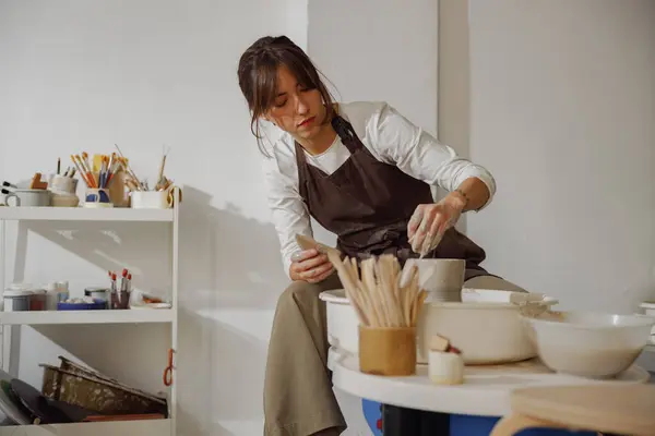 Professional female artisan shaping clay bowl in pottery studio. Ceramics art concept