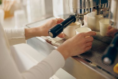 Barista kahve makinesini profesyonel kahve dükkanında iki fincanı espresso ile doldurmak için kullanır.
