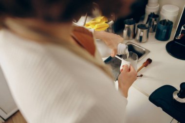 Kapuçino yapmak için baristanın metal sürahiye süt dökmesine yakın çekim. Yüksek kalite fotoğraf