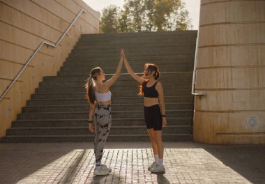 Mutlu bayan arkadaşlar dışarıda egzersiz yaptıktan sonra el sıkışıyorlar.