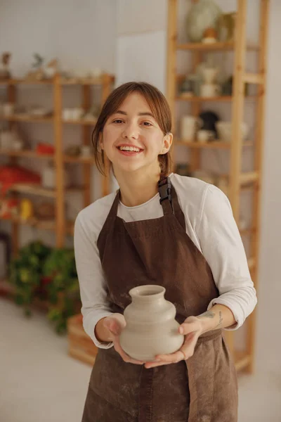 Smiling entrepreneur crafts woman holding mug in pottery studio while looking at camera