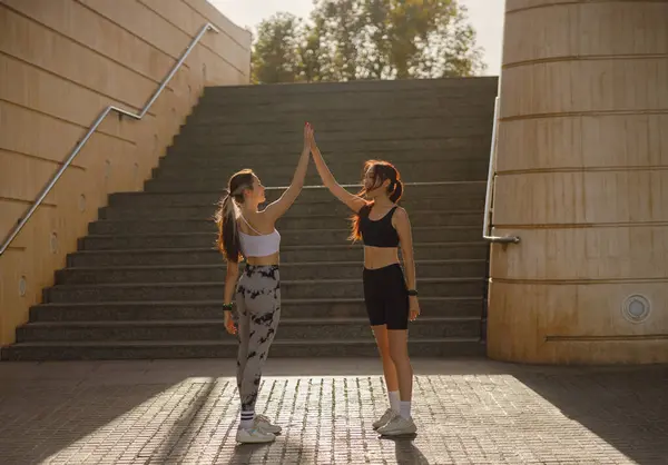 Mutlu bayan arkadaşlar dışarıda egzersiz yaptıktan sonra el sıkışıyorlar.