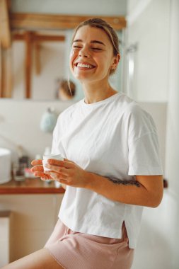 Güzel genç bir kadın banyoya nemlendirici krem sürerek cildine iyi bakıyor.