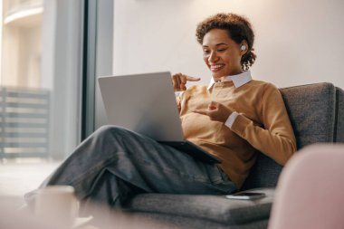 Pozitif kadın serbest çalışan gün boyunca rahat bir iş yerinde otururken online toplantı yapıyor.