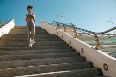 Spor giyimli atletik kadın sabahın erken saatlerinde şehirde koşuyor. Hedefe ulaşılıyor.