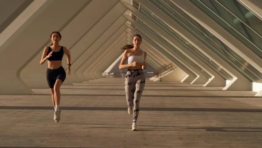 Güneşli bir günde spor giyim kuşamında açık havada koşan sportif bayan arkadaşlar. Sabah koşusu