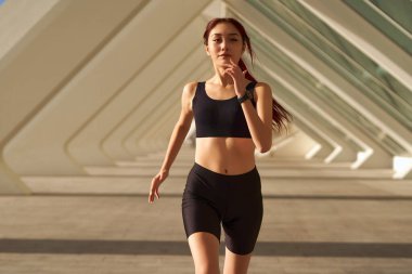 Spor giyimli atletik kadın sabahın erken saatlerinde şehirde koşuyor. Hedefe ulaşılıyor.