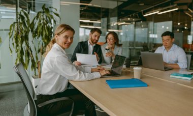 Yetenekli bir ekip modern bir ofiste, hedeflerine ulaşmak ve başarı sağlamak için ileri teknolojiyi kullanarak işbirliği yapıyor.