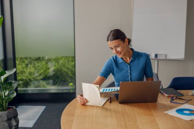 Kendini işine adamış ve yetenekli bir profesyonel. Gerekli notlar ve canlı bir ofis ortamında bir dizüstü bilgisayar.