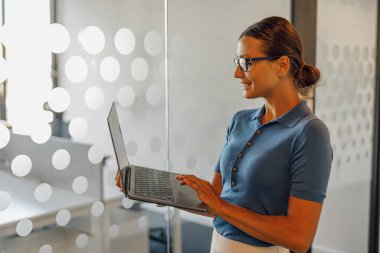 Modern bir ofiste bilgisayarını kullanan profesyonel bir kadın verimliliğini ve verimliliğini gösteriyor.