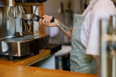 Yetenekli bir barista tekniklerini canlı bir kafede espresso makinesinde sergiliyor.