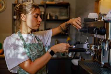 Büyüleyici bir kafede ustalıkla kahve yapan odaklanmış bir barista.