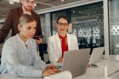 Kendini işine adamış bir ekip, dijital görevlere odaklanmış modern bir ofis ortamında verimli bir şekilde çalışıyor ve işbirliği yapıyor.