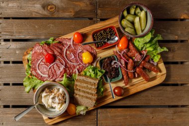 Çeşitli etlerden, renkli sebzelerden ve nefis baharatlardan oluşan bir şarküteri tahtası.