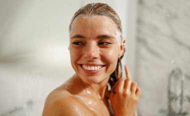 Neşeli, genç bir kadın canlandırıcı bir duştan zevk alıyor, kendine güveni, sağlığı ve genel olarak sağlıklı.