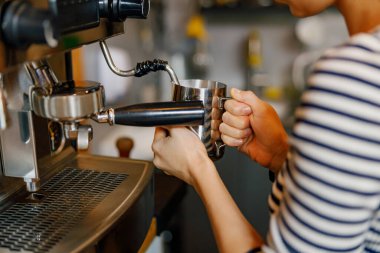 Kahve makinesiyle rahat bir kafede espresso demleyen yetenekli bir barista.