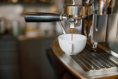 Espresso makinesinden el değmemiş beyaz bir fincana dökülen yakın çekim bir espresso görüntüsü.