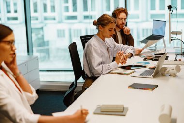 Çağdaş bir ofis ortamında, iletişim ve yaratıcılığı sergileyen çeşitli bir ekip işbirliği yapar..