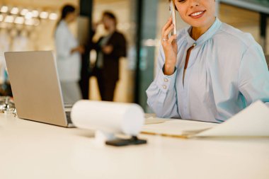 Kendini işine adamış profesyonel bir kadın, modern ofis ortamında çalışırken önemli bir telefon görüşmesi yapar.