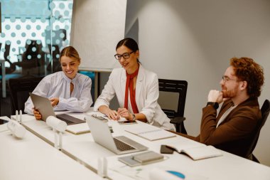 Çağdaş bir ofis çalışma alanı ortamında etkileşimli bir işbirliği toplantısına katılan bir grup profesyonel