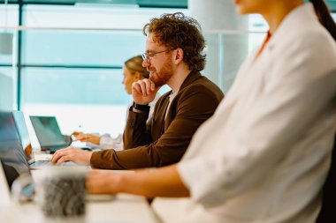 Profesyoneller modern bir çalışma ortamında dizüstü bilgisayarlarını kullanırken etkin bir şekilde takım çalışmasına girişirler.