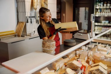 Çalışkan ve kendini işine adamış bir çalışan canlı bir peynir dükkanında çeşitli kaliteli peynirler sergiliyor.