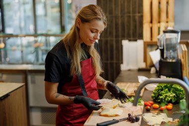 Çok yetenekli bir şef, çok güzel tasarlanmış çağdaş mutfak ortamında canlı ve taze sebzeleri ustalıkla dilimler.