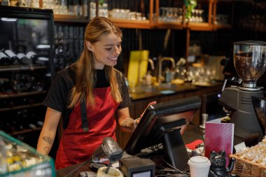 Neşeli bir barista, hareketli bir kahve dükkanında modern bir noktasal satış sistemini ustalıkla kullanıyor.