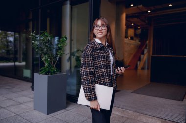 Kendine güveni tam ve stil sahibi profesyonel bir kadın ofis binasının dışında duruyor. Kendine güveni tam.