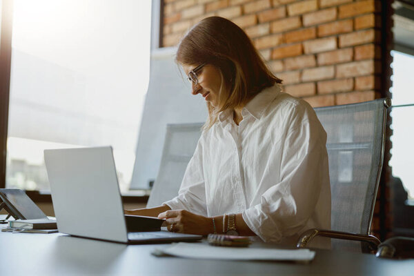 Целенаправленная женщина, печатающая на ноутбуке в стильной офисной обстановке, демонстрирующая производительность и креативность.
