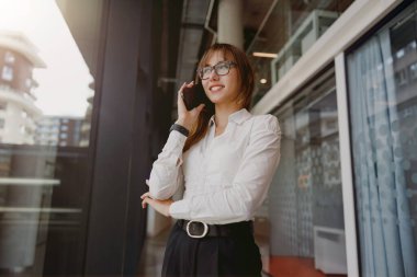 Şık bir kadın telefon görüşmesi yapar, profesyonellik ve modern ofis estetiğini gösterir..