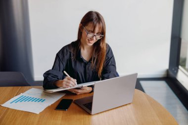 Kendini işine adamış genç bir profesyonel, çağdaş ofis ortamında yoğun bir şekilde işine odaklanmış durumda.