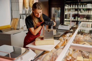 Çok yetenekli bir zanaatkar, canlı bir gurme dükkanında çeşitli lezzetli peynirleri ustalıkla dilimliyor.